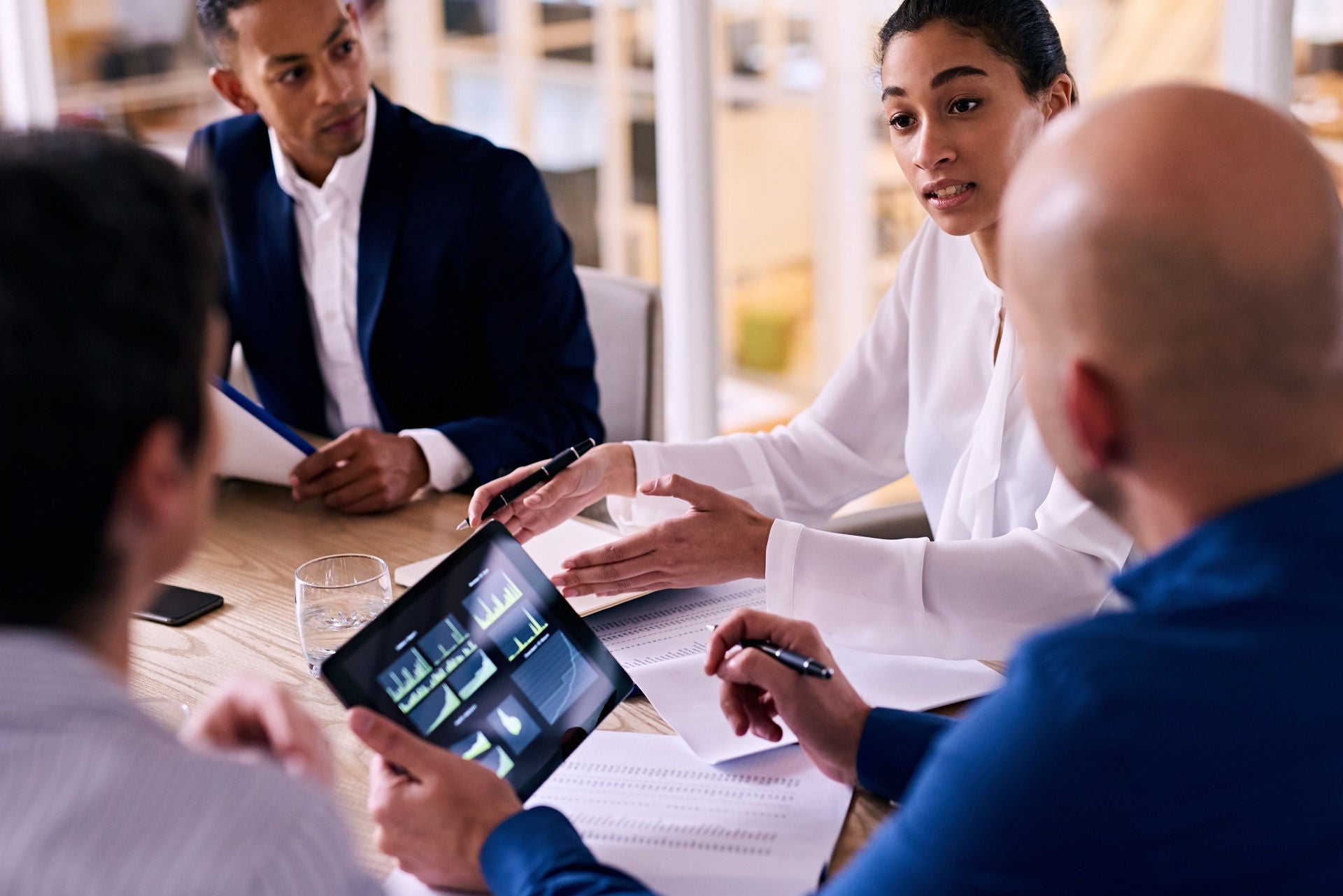 Business meeting between four upper management board members in the new modern office conference room with technology integrated in the form of an electronic tablet.; Shutterstock ID 471064346; purchase_order: -; job: -; client: -; other: -