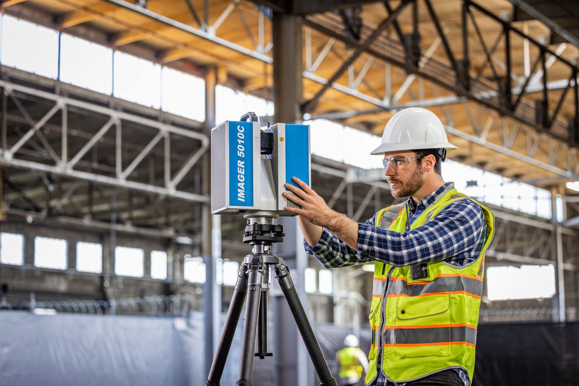 Mann mit Warnweste und Laserscanner in Fabrikhalle