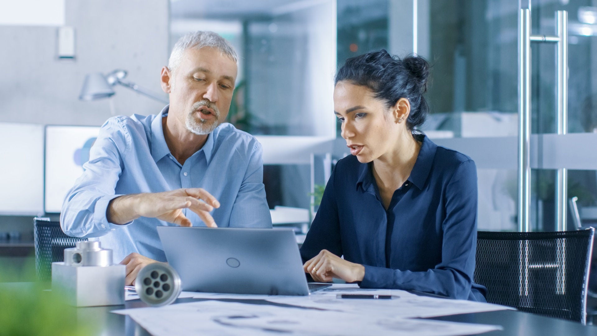 Experienced Male and Female Industrial Engineers have Discussion, Making Adjustment and Perfecting Parts, Type Corrections on a Laptop, They Work on a Machinery Component Design.