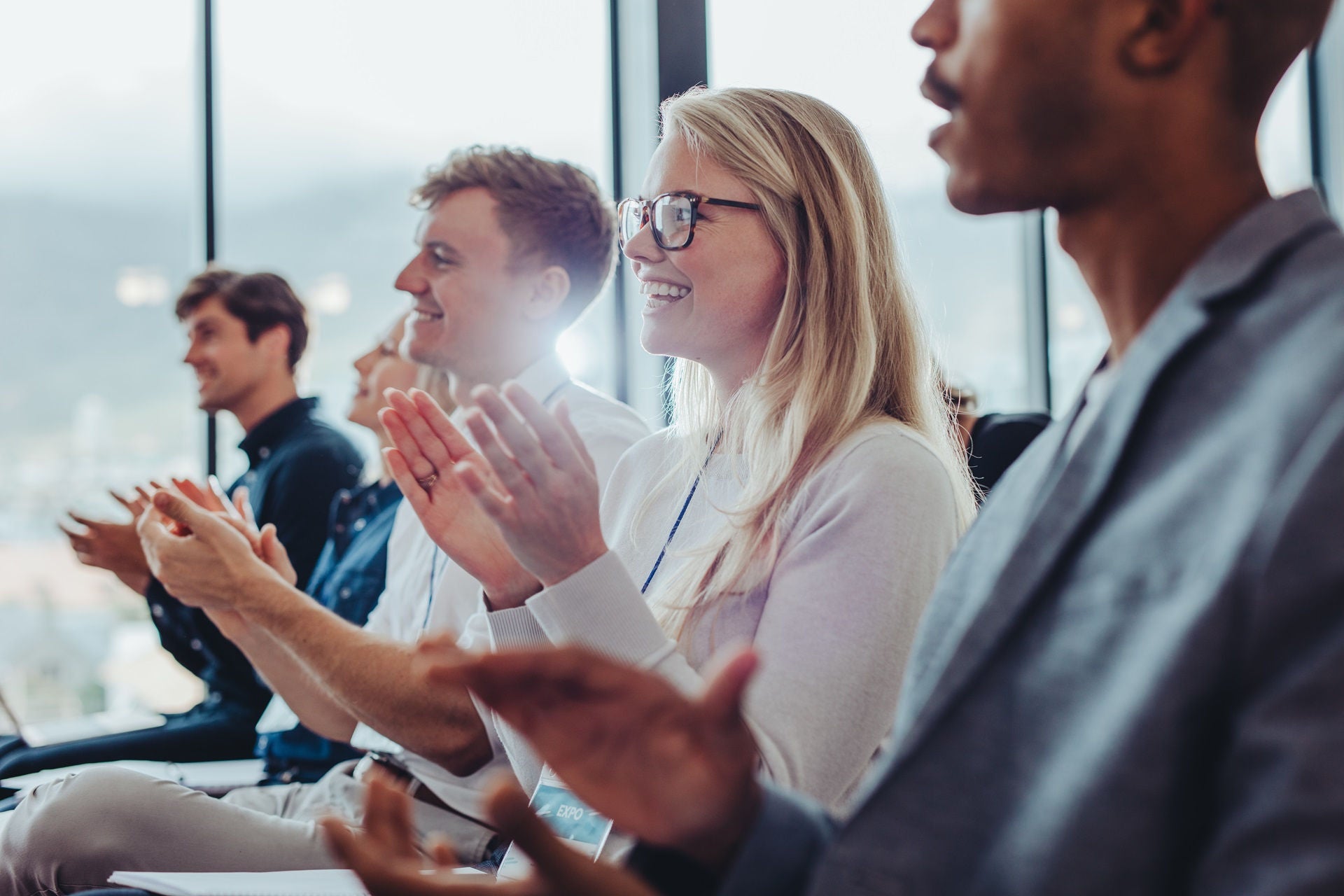 Group of businessmen and businesswomen sitting in audience clapping hands during a presentation. Businesspeople applauding in a conference.